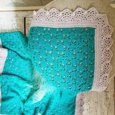 a crocheted blanket is laying on a wooden surface