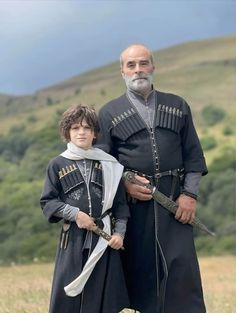 an older man and young boy dressed up in medieval clothing, standing next to each other