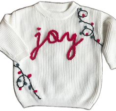 a white sweater with the word joy written on it's chest and red lettering