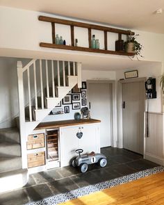 a living room with stairs and pictures on the wall next to a wooden flooring