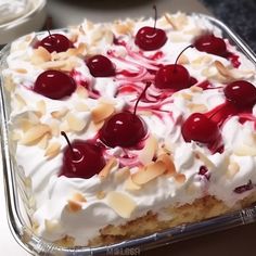 a cake with white frosting and cherries on top is sitting in a pan