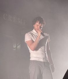 a man standing in front of a microphone on stage