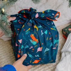 a person holding a wrapped present under a christmas tree