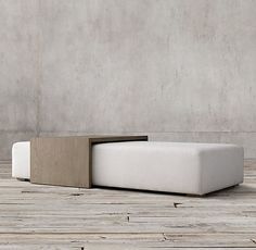 a white couch sitting on top of a wooden floor next to a cement wall with an opening in the middle