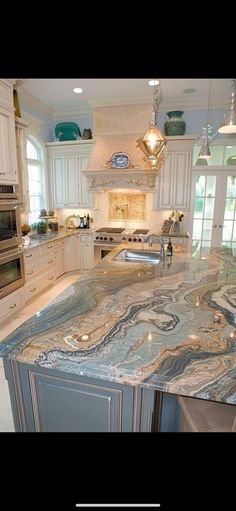 a large kitchen with marble counter tops and white cabinets, along with an island in the middle