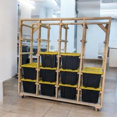 several black and yellow bins are stacked on a wooden rack in the middle of a room