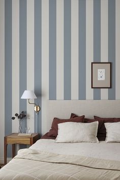 a bedroom with striped wallpaper and a bed in the foreground, two nightstands on either side