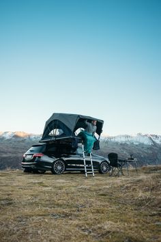 a man standing on top of a car next to a ladder