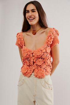 a woman wearing an orange top with crocheted flowers on the front and back