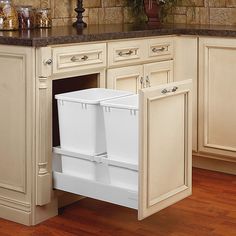 a kitchen with white cabinets and an open dishwasher in the center, on top of a wooden floor