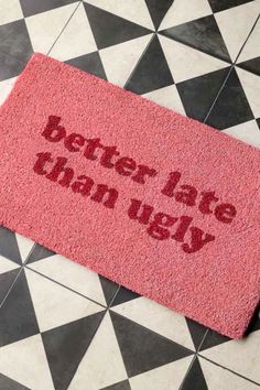 a pink door mat that says better late than ugly on the floor next to a black and white checkered floor