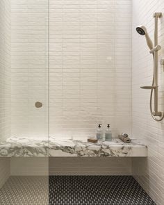 a bathroom with a marble counter top and shower head in the corner, along with black and white tile flooring