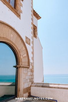 an open door leading to the ocean from a stone building with arched doorways and windows