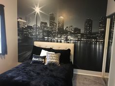 a bedroom with a black and white city skyline wallpapered on the wall behind it