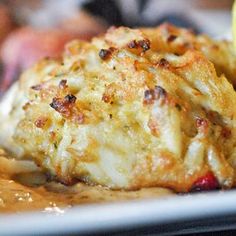 a plate topped with chicken covered in gravy next to a lemon wedge