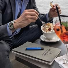 a man sitting at a table eating food with a drink in front of him,