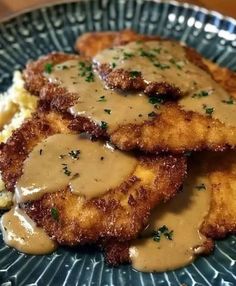 some fried chicken with gravy on top of mashed potatoes and gravy