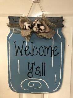 a welcome yall sign hanging on the front door with a burluck bow