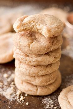 a stack of cookies sitting on top of a wooden table covered in powdered sugar