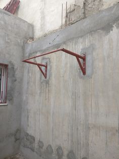 the corner of a building with two red metal brackets attached to it's walls