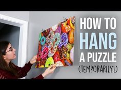 a woman holding up a piece of art with the words how to hang a puzzle on it