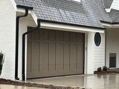 a white house with two brown garage doors