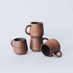 three brown mugs sitting next to each other on a white surface with no one around them