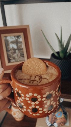 a person holding a mug with a cookie in it