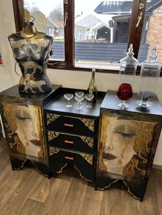 two sideboards with paintings on them in front of a window and vases next to each other