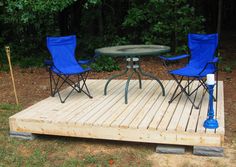 two blue chairs sitting on top of a wooden deck next to a table and umbrella