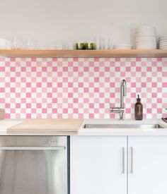 a pink and white checkered backsplash in a kitchen with stainless steel dishwasher