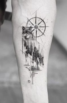 a man's leg with a wolf and compass tattoo on it