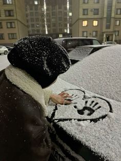 a person standing next to a car covered in snow and frost with mickey mouse drawn on it