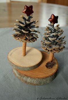 two small pine trees are sitting on a wooden stand, one is made out of wood