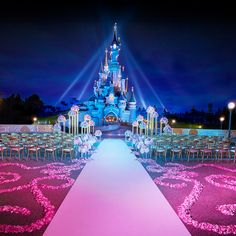 an image of a castle at night with pink flowers on the aisle and lights in the background