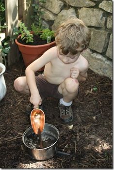 a little boy that is kneeling down with a spoon in his hand and potted plant behind him