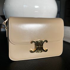 The Bag Features An Adjustable Leather Shoulder Strap With Gold Hardware, And A Matching Gold Press Lock On The Crossover Flap. This Opens To A Partitioned Beige Leather Interior With Zipper And Patch Pockets. Designer Beige Flap Bag With Gold-tone Hardware, High-end Beige Shoulder Bag For Evening, Beige Shoulder Bag With Palladium Hardware For Evening, Timeless Cream Shoulder Bag With Palladium Hardware, Luxury Calf Leather Flap Bag With Palladium Hardware, Beige Evening Shoulder Bag With Palladium Hardware, Elegant Tan Shoulder Bag With Dust Bag, High-end Beige Shoulder Bag With Branded Hardware, Timeless Beige Shoulder Bag With Branded Hardware