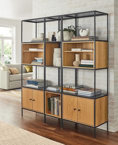 an open shelving unit in a living room with wood flooring and white brick wall