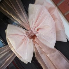 two large pink bows hanging from the side of a door with glitters on them