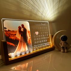 an illuminated photo frame with a calendar on it and a small figurine next to it