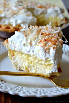 a piece of cake on a white plate with a gold fork in front of it