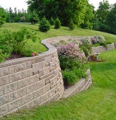 a stone wall in the middle of a grassy field