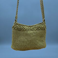 a crocheted purse hanging from a hook on a blue background with the handle down