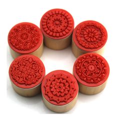 six red rubber stamps sitting in a circle on top of each other, with an intricate design