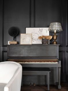 a grand piano in the corner of a room with black walls and wood flooring