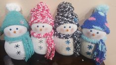 four knitted snowmen sitting on top of a table