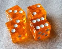 two orange dices with white dots on them sitting on a gray surface next to each other