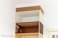 an empty closet with wooden shelves and white walls