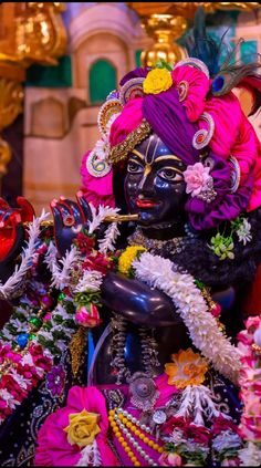 an idol is displayed in front of a building with flowers and other decorations on it