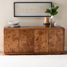 a large wooden cabinet sitting next to a wall with pictures above it and a vase on top